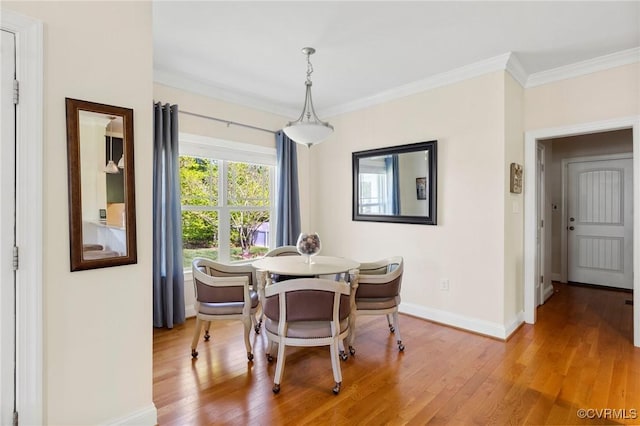 dining space with baseboards, crown molding, and wood finished floors