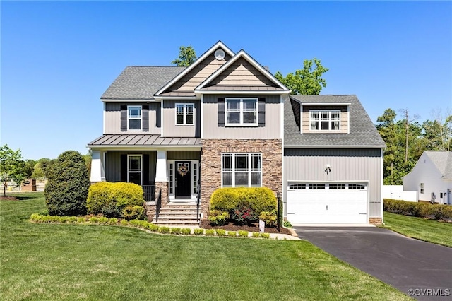 craftsman-style home featuring a standing seam roof, metal roof, a front yard, aphalt driveway, and an attached garage
