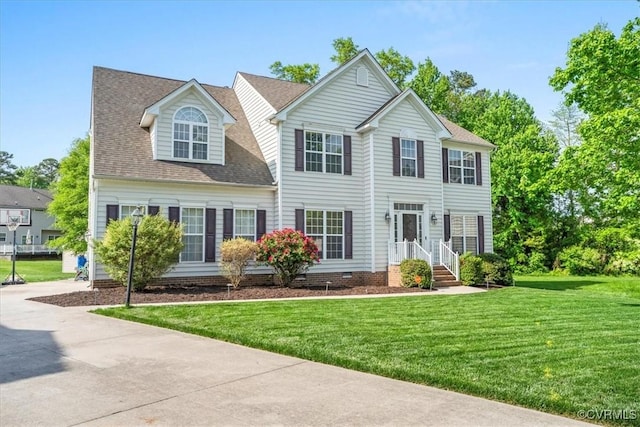 colonial home with roof with shingles, a front yard, and crawl space