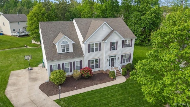 view of front of home featuring driveway, roof with shingles, and a front yard