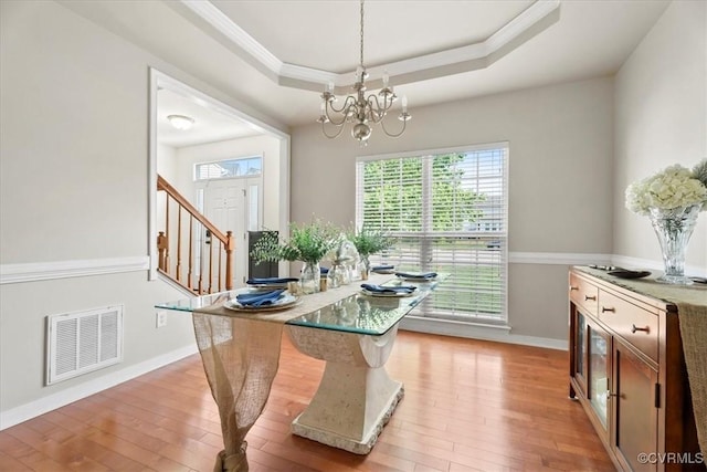 dining space featuring visible vents, crown molding, light wood-style flooring, and a notable chandelier