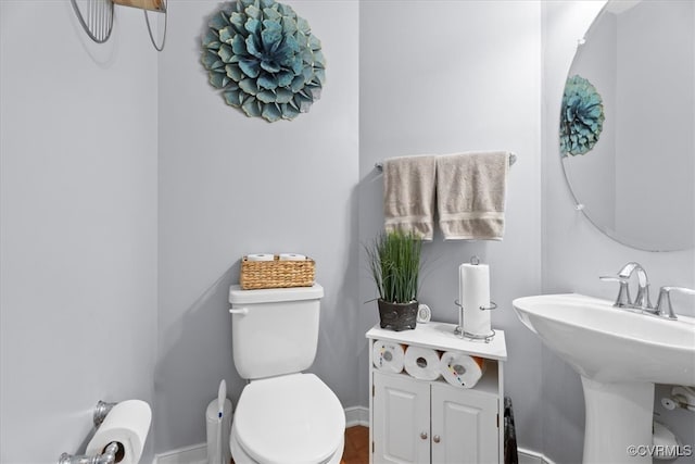 bathroom with a sink, toilet, and baseboards