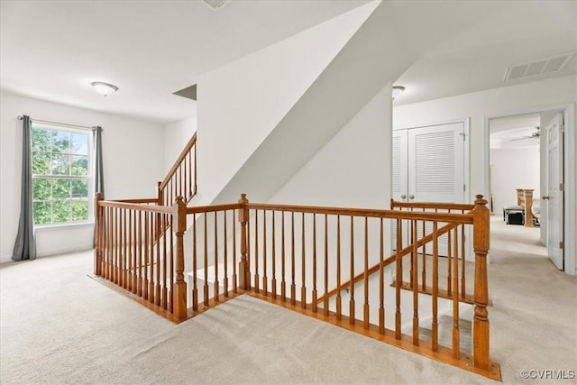 interior space featuring carpet flooring, an upstairs landing, and visible vents