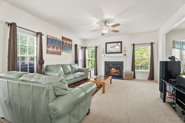 carpeted living area with a glass covered fireplace and a ceiling fan