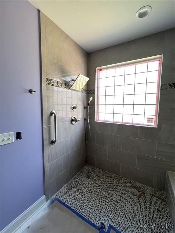 full bath featuring baseboards and a tile shower