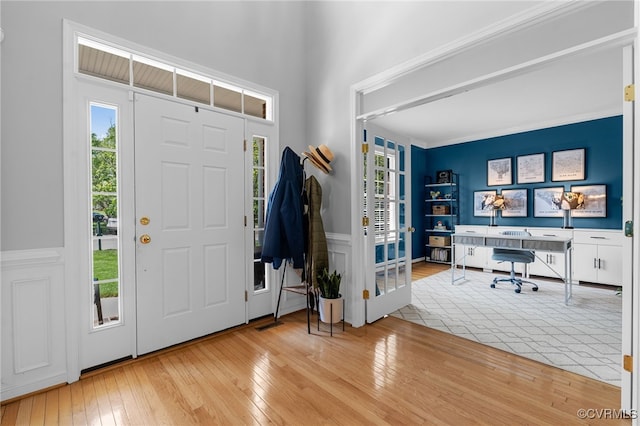 foyer featuring a healthy amount of sunlight, wainscoting, and hardwood / wood-style flooring