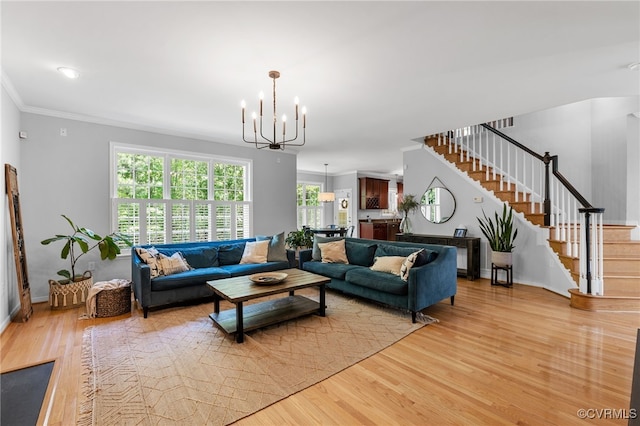 living area with a notable chandelier, a wealth of natural light, light wood-style flooring, and stairway