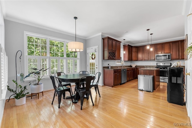 kitchen featuring a kitchen island, dark countertops, appliances with stainless steel finishes, light wood-type flooring, and a sink