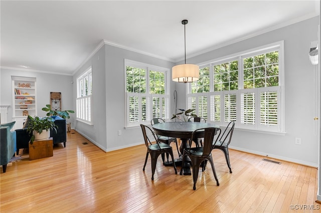 dining room featuring visible vents, built in shelves, baseboards, light wood finished floors, and ornamental molding
