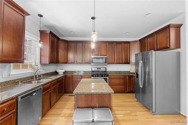 kitchen with a sink, light wood-style floors, stone countertops, stainless steel appliances, and a kitchen island