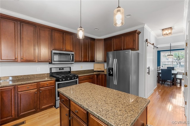 kitchen with stainless steel appliances, light stone countertops, ornamental molding, and light wood-style floors