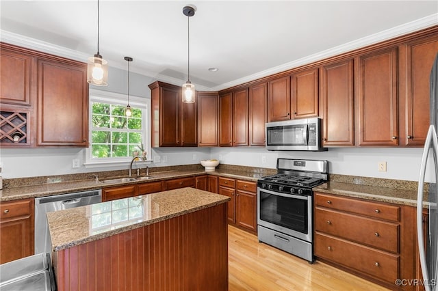 kitchen featuring a kitchen island, a sink, light wood finished floors, dark stone countertops, and stainless steel appliances