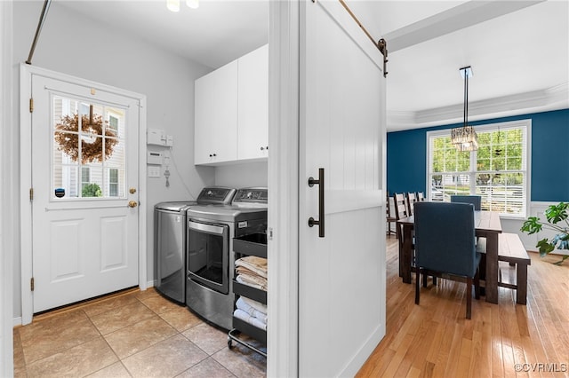 clothes washing area with an inviting chandelier, light wood-style floors, cabinet space, and washer and clothes dryer