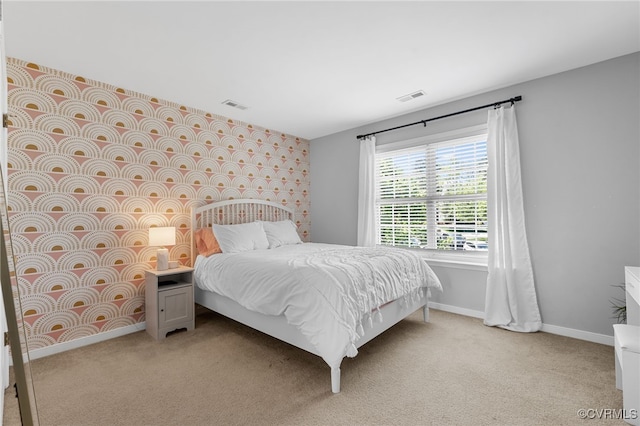 bedroom featuring baseboards, visible vents, and light carpet