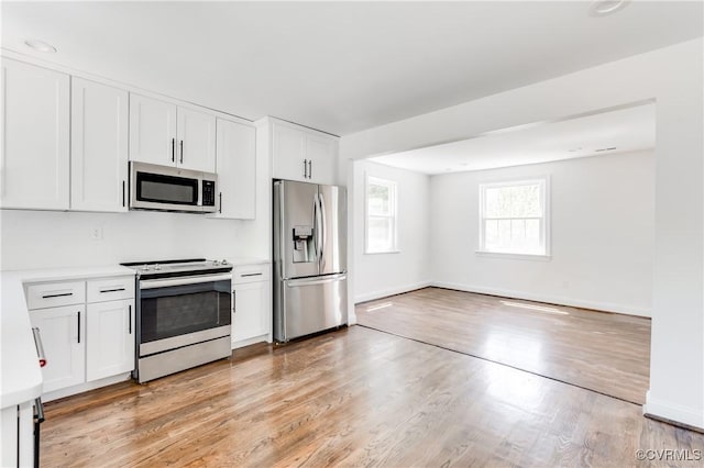 kitchen with white cabinets, stainless steel appliances, light wood-style flooring, and light countertops