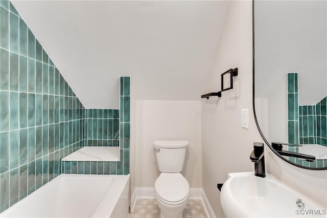 bathroom featuring baseboards, a washtub, vaulted ceiling, and toilet