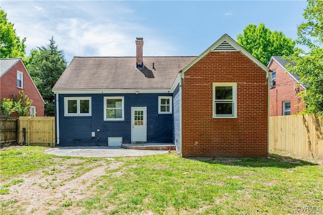 back of property featuring a lawn, a patio, a chimney, and a fenced backyard