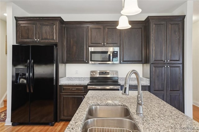 kitchen featuring dark brown cabinetry, light wood-type flooring, appliances with stainless steel finishes, and a sink
