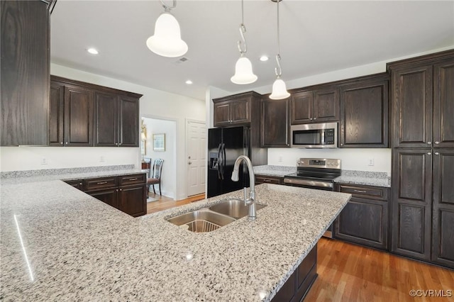 kitchen with appliances with stainless steel finishes, dark brown cabinets, and a sink