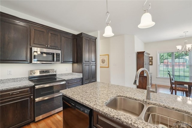 kitchen featuring stainless steel appliances, decorative light fixtures, dark brown cabinets, a sink, and a notable chandelier