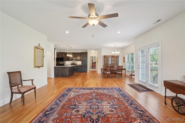 living room with visible vents, baseboards, recessed lighting, light wood finished floors, and ceiling fan with notable chandelier