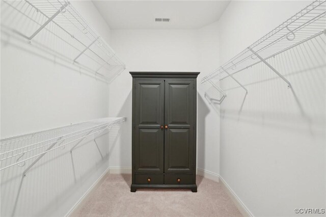 walk in closet featuring visible vents and light carpet