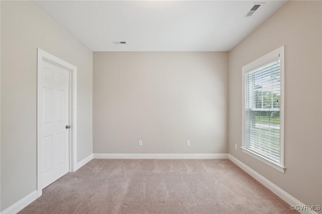 unfurnished room featuring light colored carpet, visible vents, and baseboards