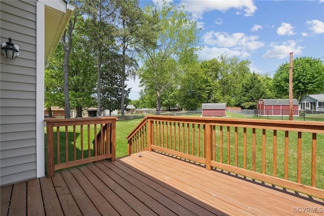 deck with a fenced backyard, an outbuilding, and a yard