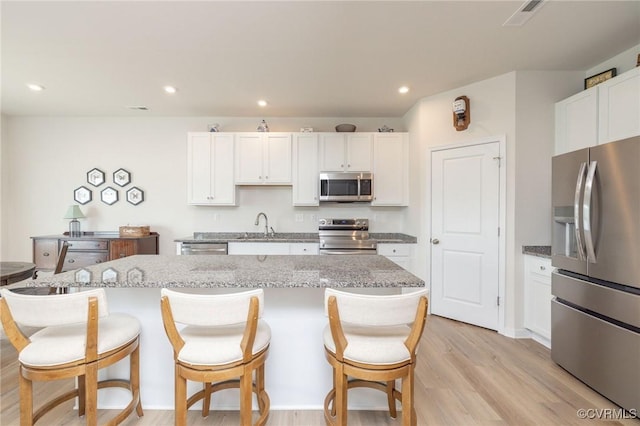 11513 Dunmore Mill Ter Unit 3-4, Chester, VA 23831 - kitchen with appliances with stainless steel finishes, a center island, white cabinets, a breakfast bar, and light wood-style flooring