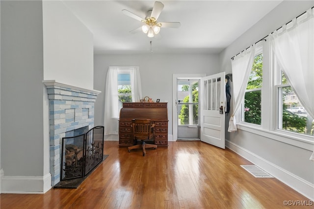 sitting room with hardwood / wood-style flooring, a fireplace, baseboards, visible vents, and a ceiling fan