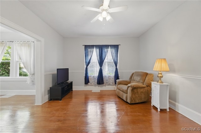 sitting room with a ceiling fan, wood finished floors, and baseboards
