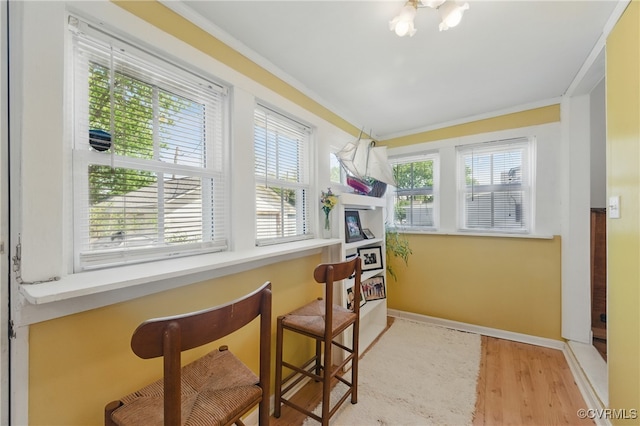 living area with crown molding, wood finished floors, and baseboards