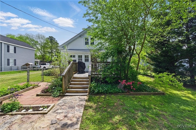 view of front facade with a front lawn, a wooden deck, and fence