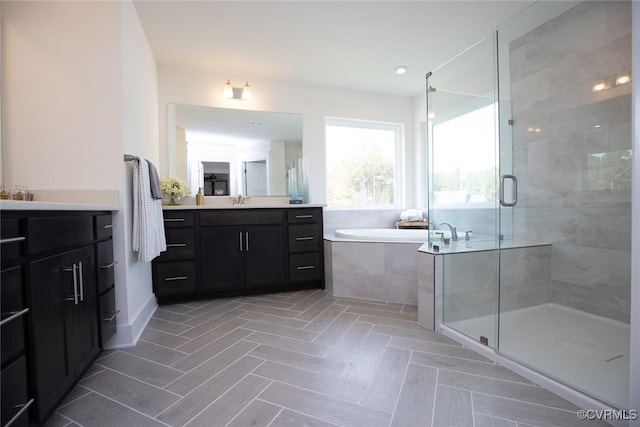 bathroom with a stall shower, a garden tub, and vanity