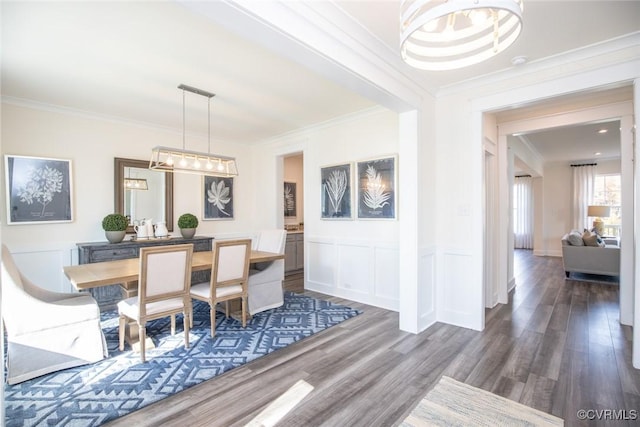dining area with an inviting chandelier, wood finished floors, and ornamental molding