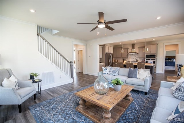 living area featuring dark wood-style floors, a ceiling fan, visible vents, and stairway