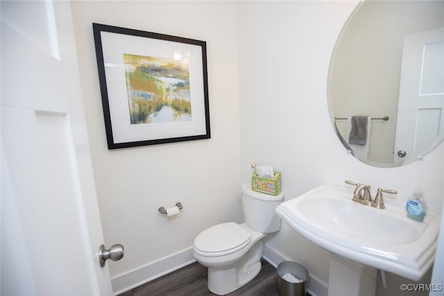 bathroom featuring a sink, wood finished floors, toilet, and baseboards