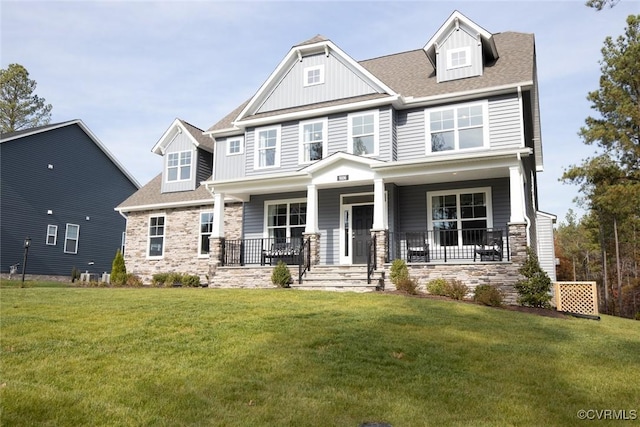 craftsman house featuring a front yard, stone siding, board and batten siding, and covered porch