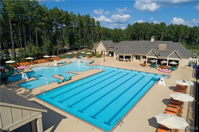 pool with a patio and a view of trees