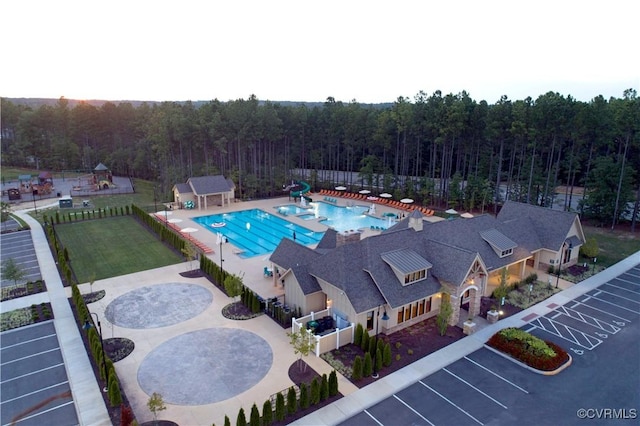 pool featuring a lawn, fence, and a wooded view