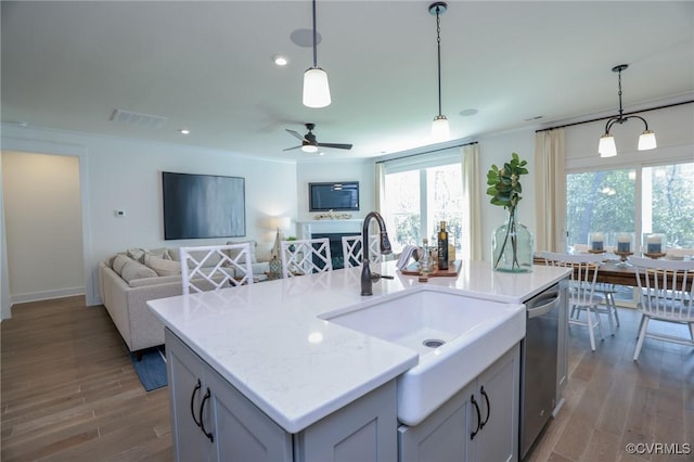 kitchen with a sink, visible vents, open floor plan, dishwasher, and wood finished floors
