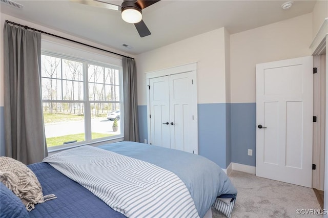 bedroom featuring light colored carpet, a closet, baseboards, visible vents, and a ceiling fan