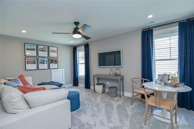 carpeted living area with a ceiling fan, visible vents, baseboards, and plenty of natural light