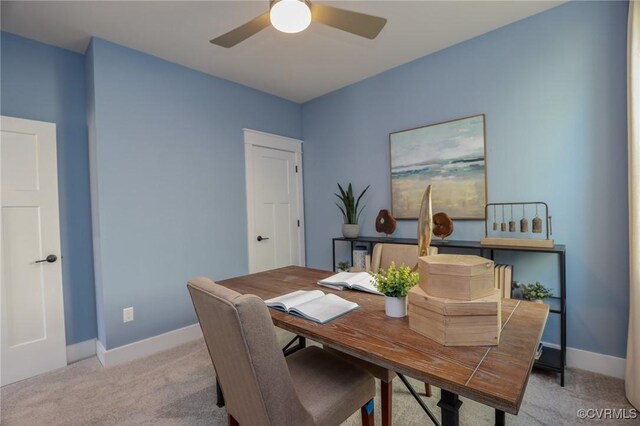 office space featuring a ceiling fan, light colored carpet, and baseboards