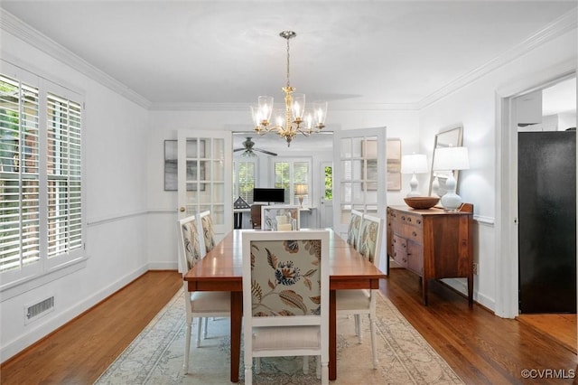 dining space with crown molding, baseboards, visible vents, and wood finished floors