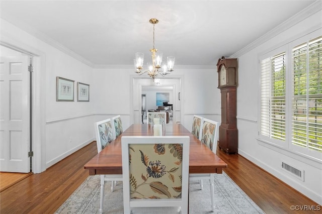 dining area featuring visible vents, wood finished floors, baseboards, an inviting chandelier, and ornamental molding
