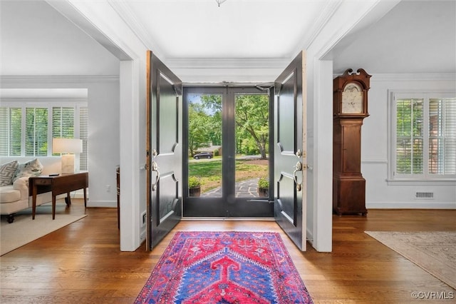 foyer entrance with visible vents, a healthy amount of sunlight, and wood finished floors