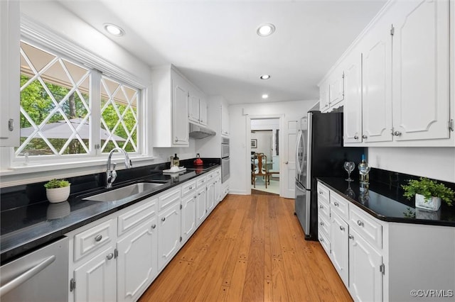 kitchen featuring dark countertops, light wood-type flooring, recessed lighting, white cabinetry, and a sink