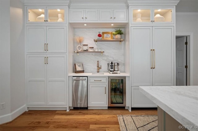 bar featuring wine cooler, a sink, indoor wet bar, tasteful backsplash, and light wood-type flooring