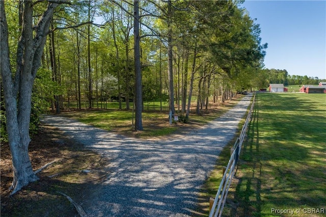 view of home's community featuring gravel driveway and fence